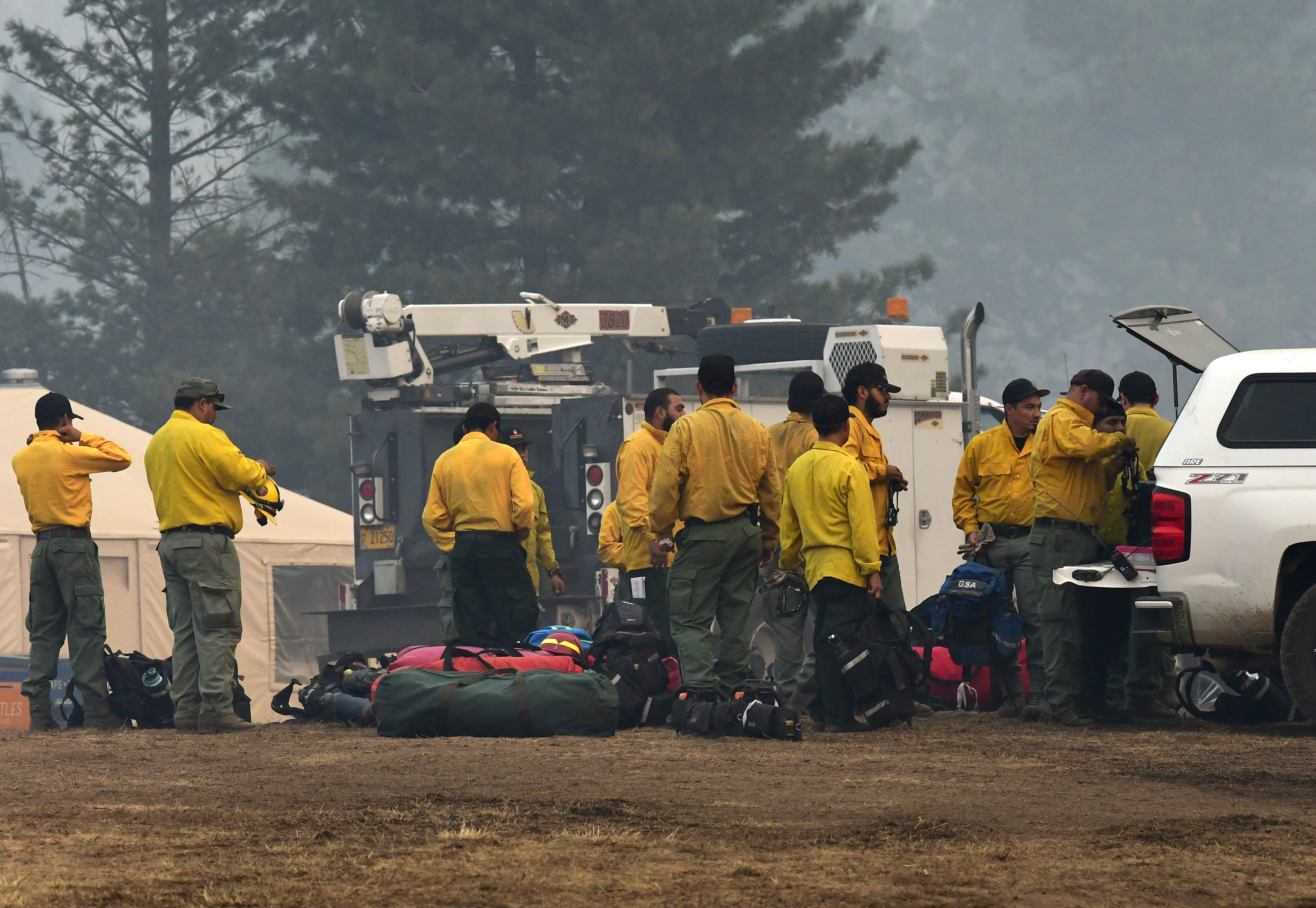 Smoke shrouds the trees as firefighters in fire-resistant Nomex clothing pack to go to the fire line at Rum Creek Fire in southwest Oregon on August 29, 2022. 