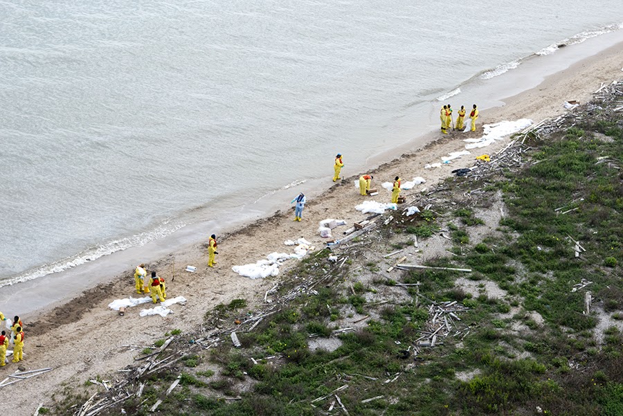 Federal and local agency workers help clean up the beaches affected by the Texas City "Y" oil spill, which resulted from a collision between a bulk carrier and a barge in the Houston Ship Channel.
