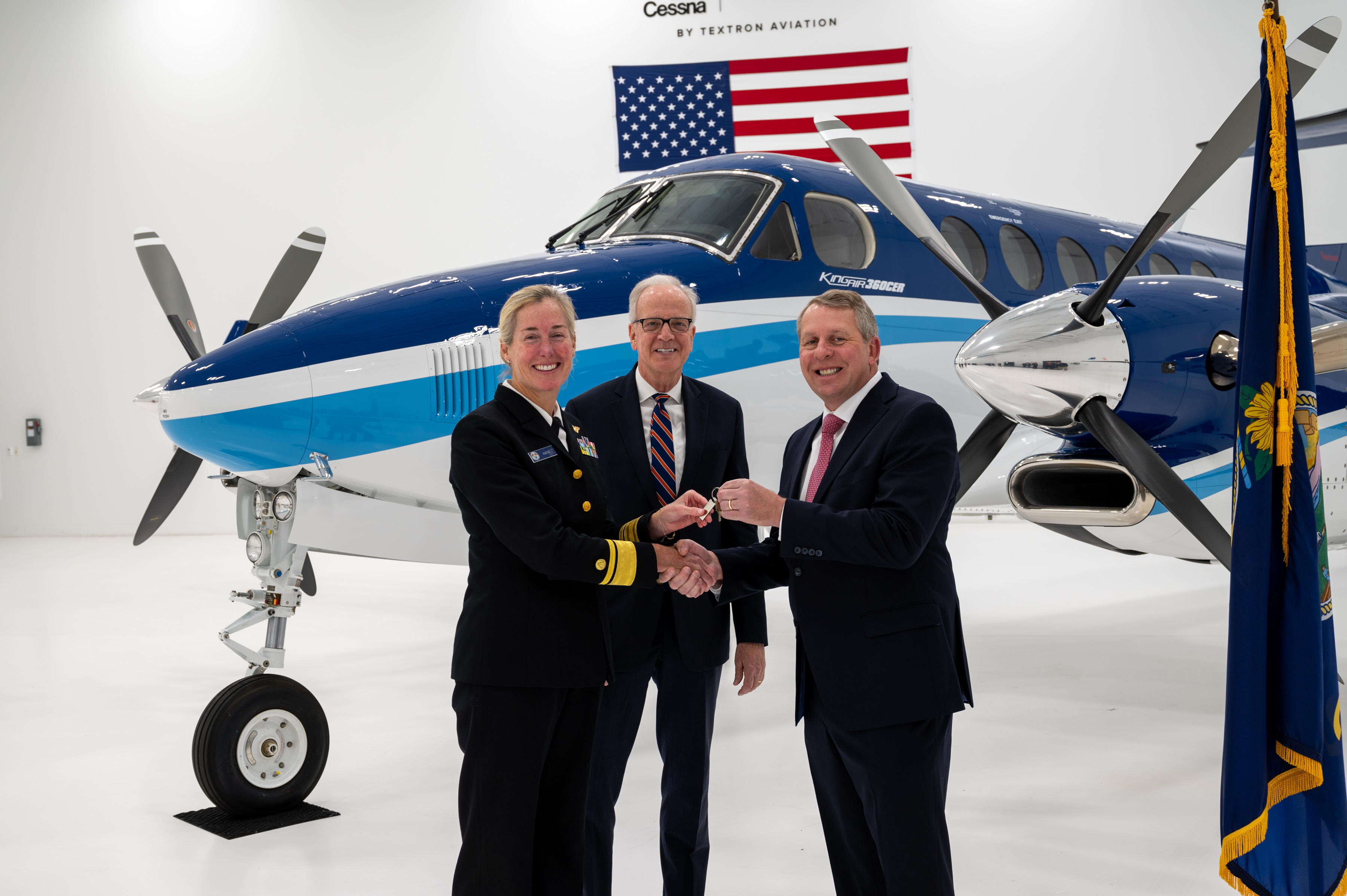 Photo showing Rear Adm. Nancy Hann (left) receives the key to Beechcraft King Air N65RF from Ron Draper (right), president and CEO of Textron Aviation, with Senator Jerry Moran (center). Credit: Textron Aviation