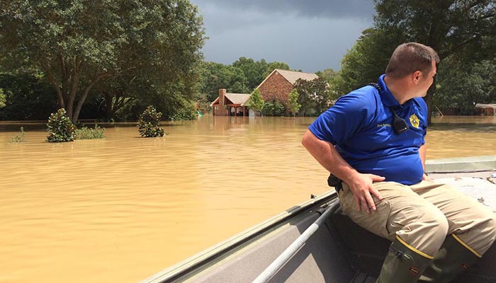 A Livingston Parish deputy sheriff surveys flood damage from a boat on August 15, 2016.