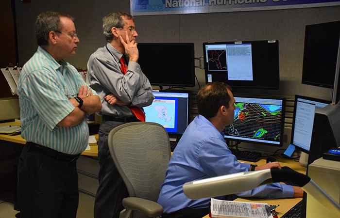 The complete advisory package is issued every six hours. On September 2, Senior Hurricane Specialist Dr. Michael Brennan writes the public advisory for Hermine as Chief of forecast operations James Franklin and Deputy Director Dr. Ed Rappaport look on. 