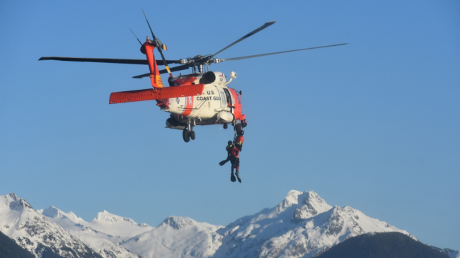 Photo of a U.S. Coast Guard Air Station Sitka rescue swimmer hoists a Royal Canadian Air Force search and rescue technician while conducting joint training in Sitka Sound, Alaska, Feb. 17, 2019.