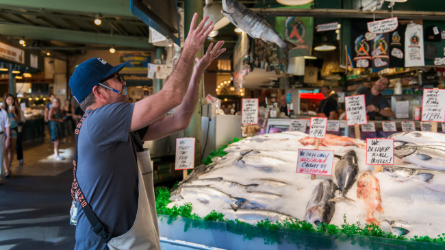 A fish Monger at Pike Place Market catching a fish for tourists late in the day.
