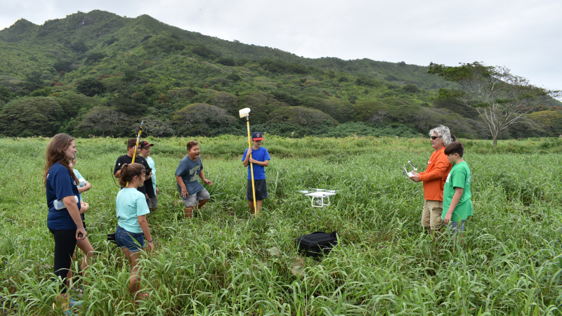 Kaohao Public Charter School students react to the launch of an Unmanned Aerial Vehicle (UAV) that the students are using to map the Kawainui Marsh in Kailua, Hawaii. After they collect the map generated from the UAV’s flight, the students will trek through the marsh themselves to ground truth the map and align their collected water quality samples with it. This project is part of the Watershed Investigations, Research, Education, and Design (WIRED) Project, run by the Pacific American Foundation and