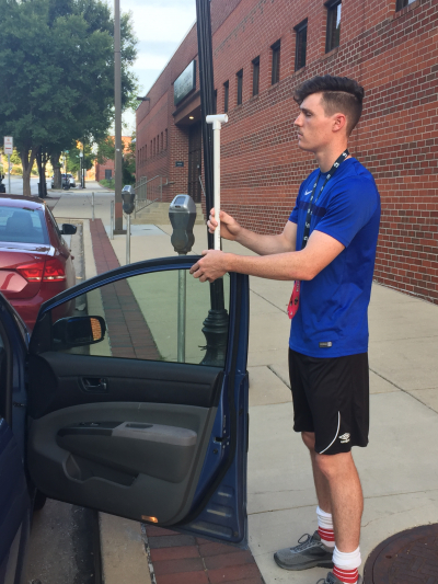 Luke Hanno, a high school senior from Bowie, Maryland, and citizen scientist/volunteer driver for the Baltimore Urban Heat Island Mapping project, mounts a special temperature sensor in the passenger-side window of his car just prior to driving his assigned route in Baltimore. Photo date: August 29, 2018.