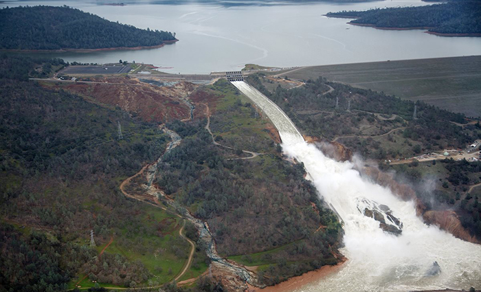 This aerial view looks east toward Oroville Dam and Lake Oroville, showing the damaged spillway with its outflow of 100,000 cubic feet per second (cfs) at the Butte County site. The California Department of Water Resources has a goal to lower the lake level by 50 feet to handle the next round of winter storms. Photo taken February 15, 2017. 