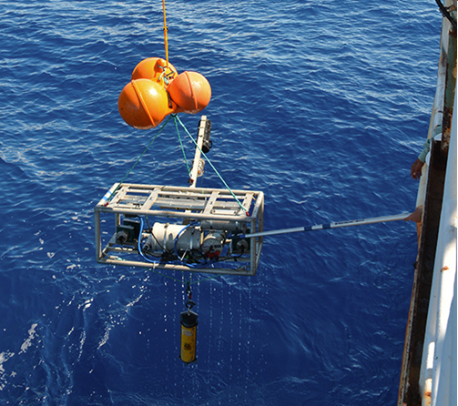 An underwater camera system is lowered into the ocean from a ship.