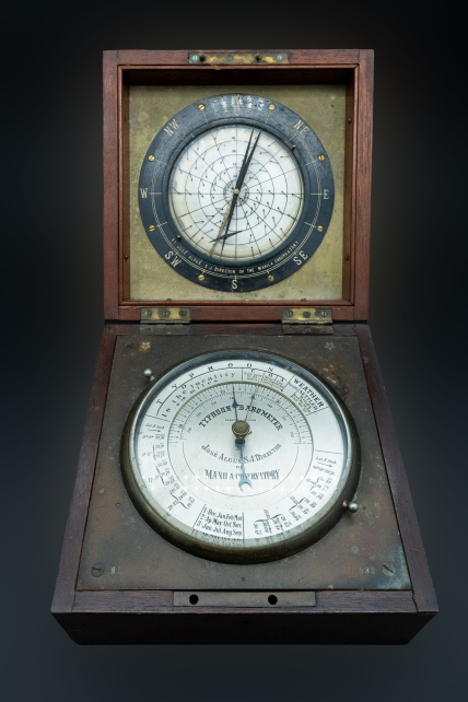 An early 20th century barocyclonometer, open to reveal a barometer on the bottom half and a cyclonometer on the top half.