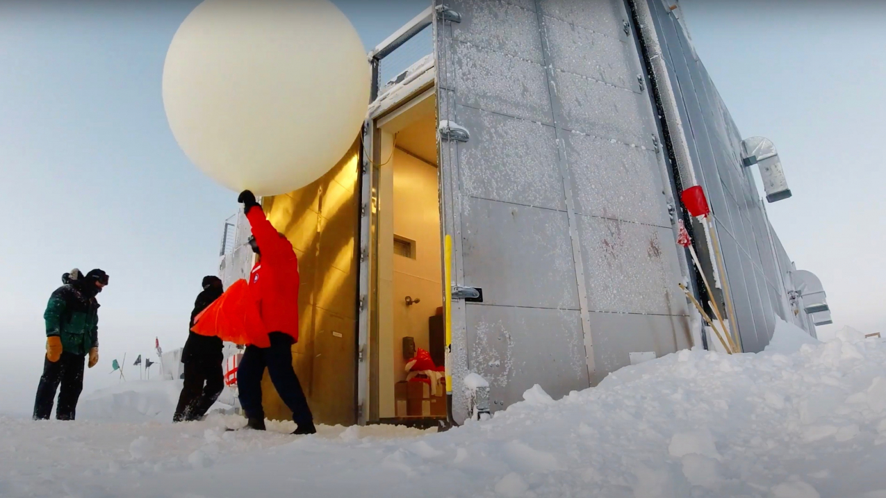 Lt. Timothy Holland, NOAA Corps, emerges from a balloon assembly station with an ozonesonde attached to a weather balloon before releasing it over the South Pole.