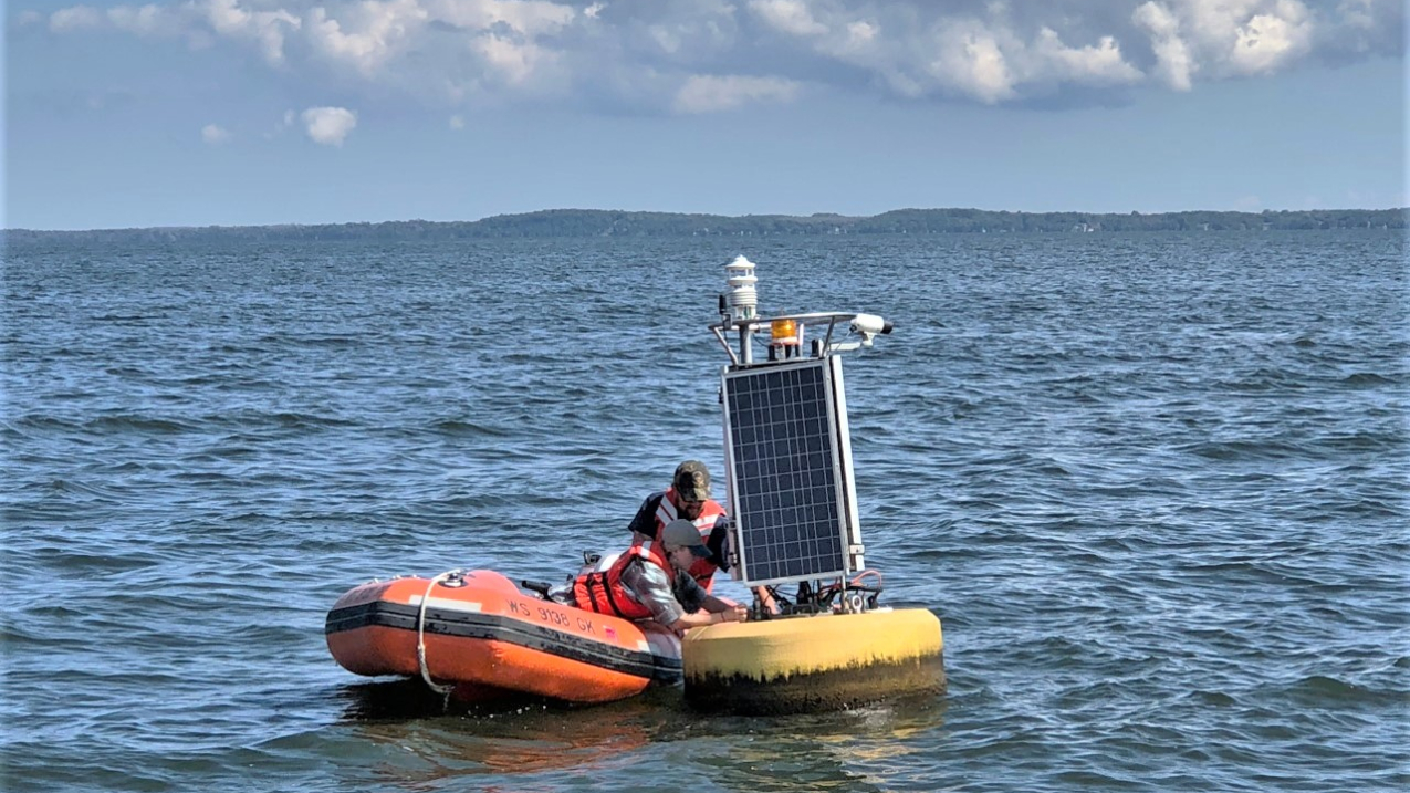Two men in small launch repair buoy in Lake Michigan