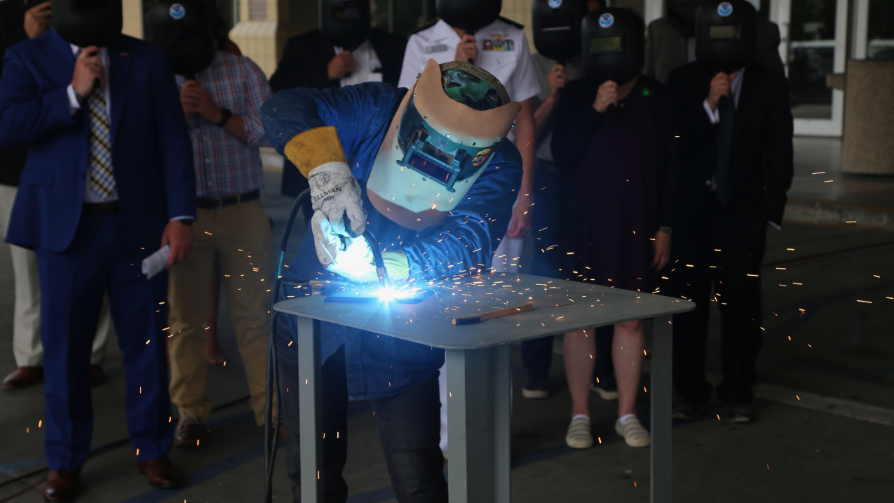 A welder from Thoma-Sea Marine Constructors, LLC, welds the initials of the Oceanographer's sponsor, Linda Kwok Schatz, onto a steel plate that will be incorporated into the ship in keeping with maritime tradition. 