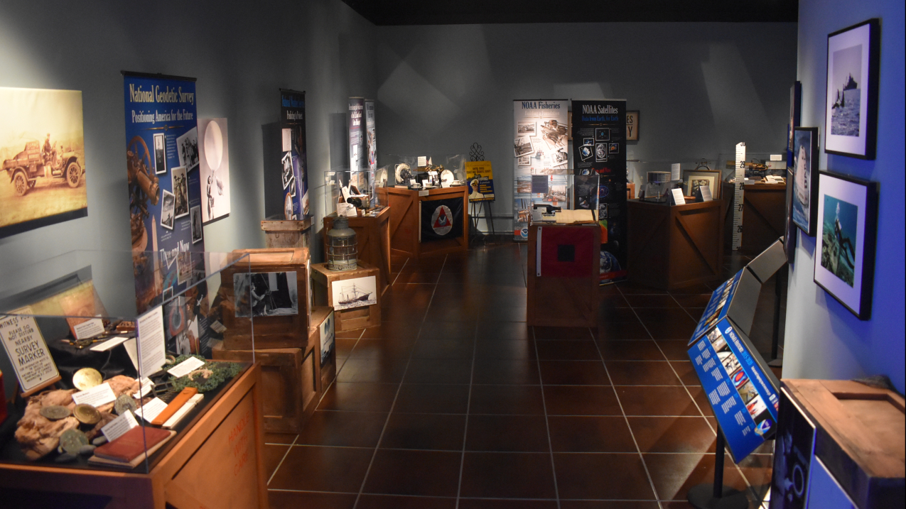 The Treasures of NOAA's Ark exhibit on display at the Tellus Science Museum in Atlanta, GA. Several cases are spread throughout the room, with maps, and charts, early scientific instruments, and other historical artifacts inside them.