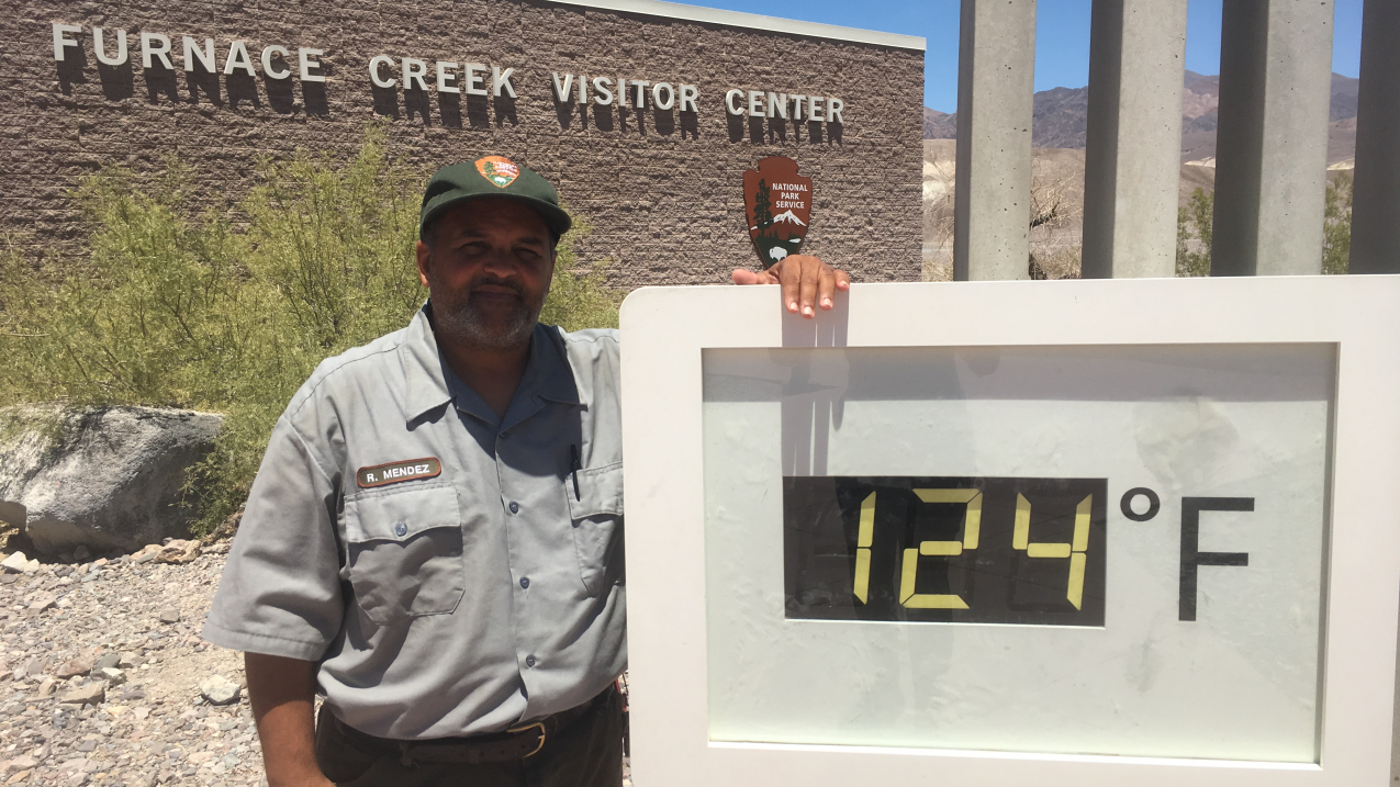 Park Ranger Roberto Mendez stands next to the unofficial temperature display outside Furnace Creek Visitor Center at Death Valley National Park in California on June 18, 2017. On both June 20 and 24, the temperature reached 127 degrees F, setting an all-time record high temperature for the month of June. During the evening, it only cooled to 97 and 98 degrees, respectively.