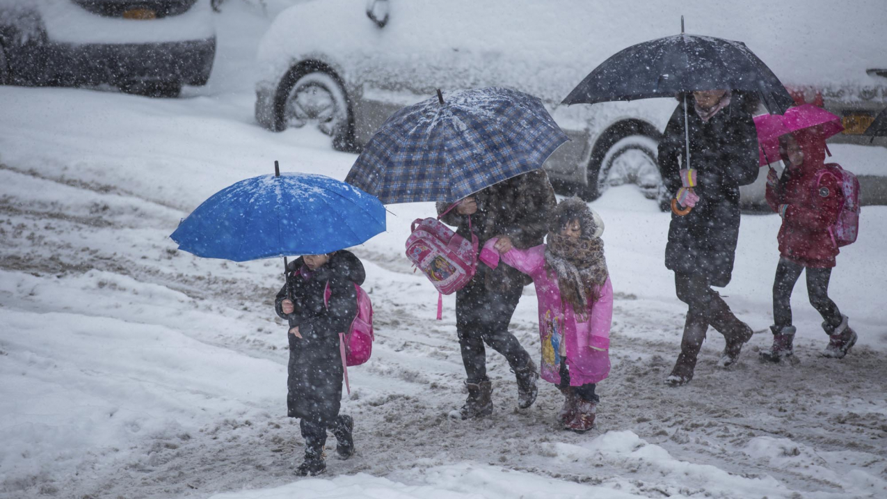 Brooklyn, NY, USA - February 13, 2014: Mothers escorting their children to school in a snow storm in Borough Park, Brooklyn.