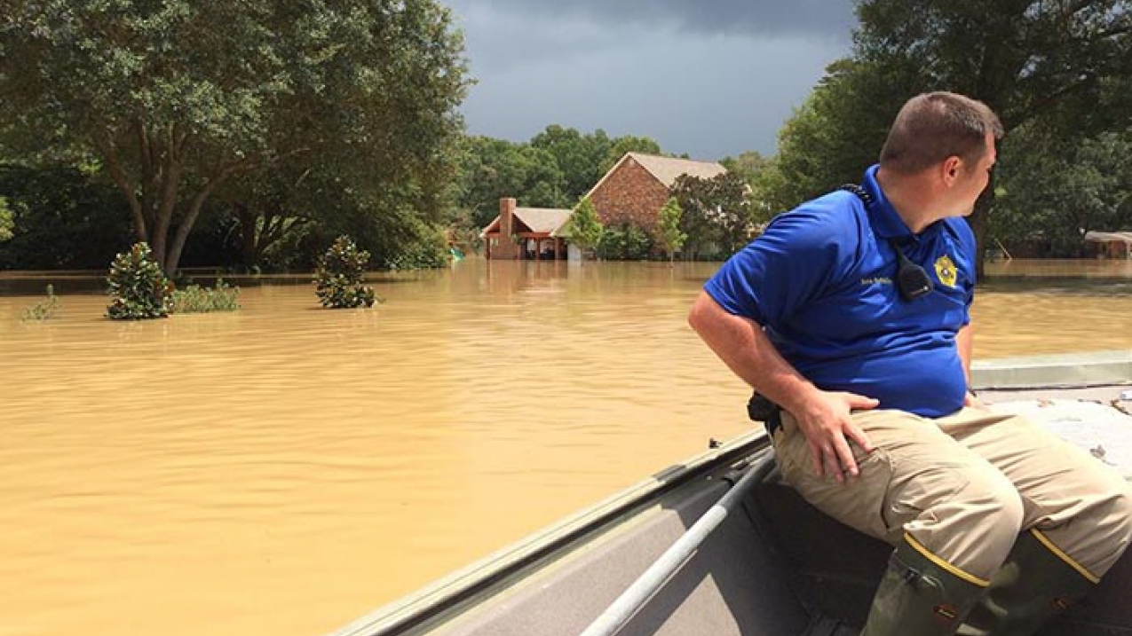 A Livingston Parish deputy sheriff surveys flood damage from a boat on August 15, 2016.