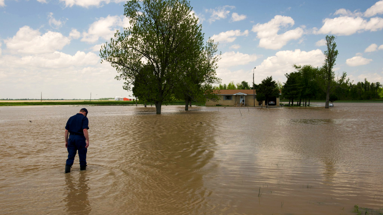 Coast Guard Reservist LT JG Ash Thorne wades into a water-covered driveway that his disaster area response team had crossed to rescue a couple trapped in their home by floodwater. Thorne assisted in the 2011 flood response in rain-soaked communities throughout Missouri, Illinois and Kentucky.