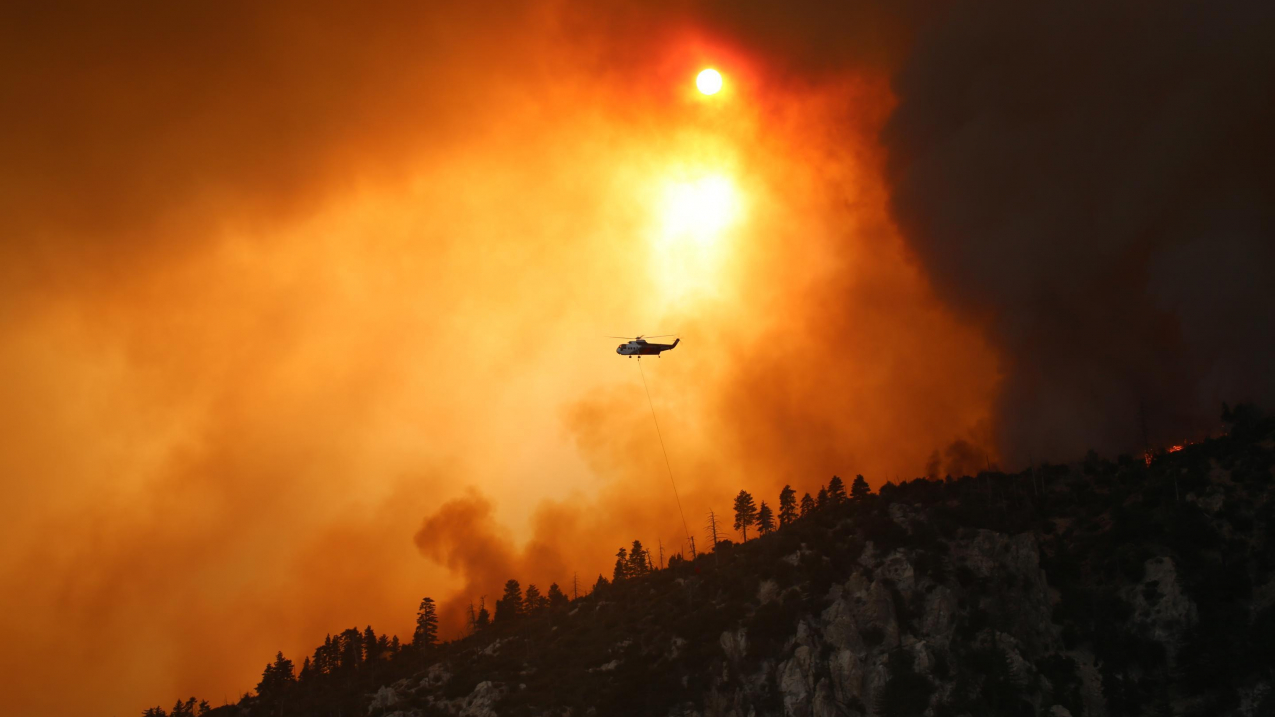California's massive Bobcat Fire started in and around Angeles National Forest on September 6, 2020. As of October 5, the fire has burned through more than 115,000 acres. In this Inciweb photo, a helicopter flies in an orange smoke-filled sky over a portion of the fire to help distinguish it. More information and photos available at Inciweb, www.inciweb.nwcg.gov/incident/7152.