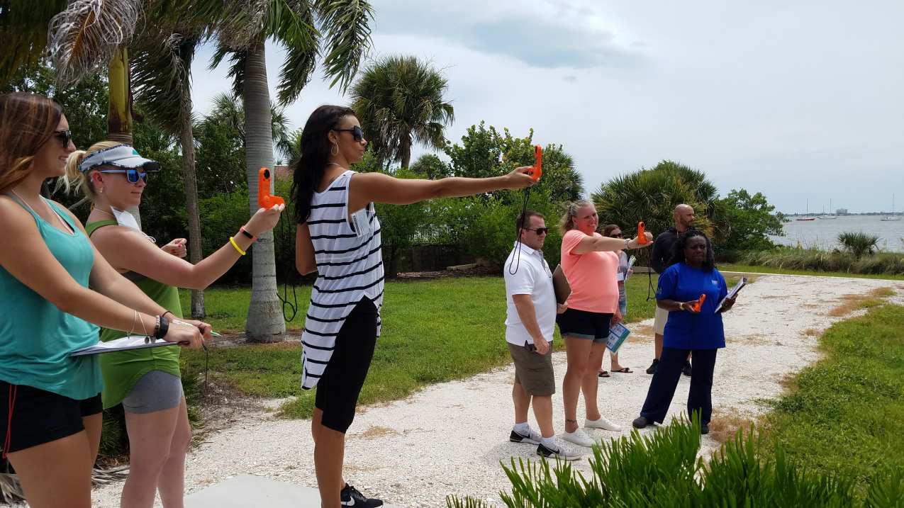 Teachers standing outside holding wind speed measuring devices.