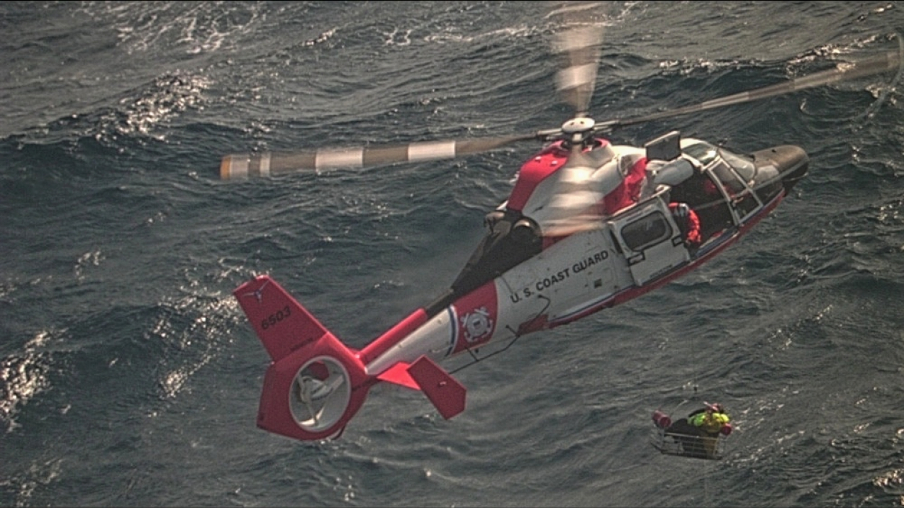 An Air Station Houston MH-65 Dolphin helicopter crew conducts a hoist of one of two mariners approximately 288 miles east southeast of Corpus Christi, Texas, on Jan. 2, 2020. The two sailors were aboard the 37-foot sailing vessel Rhapsody when it became disabled due to an engine room fire and activated their emergency position-indicating radio beacon for rescuers to locate them.