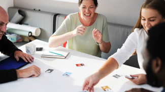 Group of colleagues laughing while working. (shutterstock)
