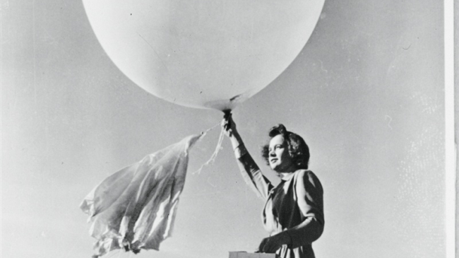 Black and white photo of a woman launching a weather balloon. 
