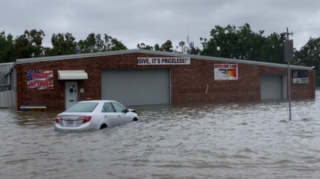 A car in front of a close business sits partially submerged in a flooded parking lot in Lake Charles, Louisiana, May 17, 2021.