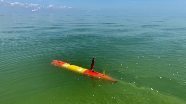 a long-range autonomous underwater vehicle underway through green, algae-rich water of Lake Erie