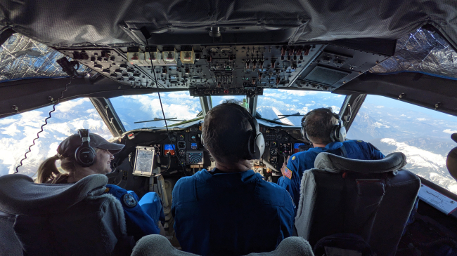 Flight station view showing Lt. Cmdr. Rebecca Shaw, Flight Engineer Lonnie Kregelka, and Lt. Cmdr. Rob Mitchell flying over Alaska in NOAA WP-3D Orion N42RF Kermit during 2021 Ocean Winds Winter research project.