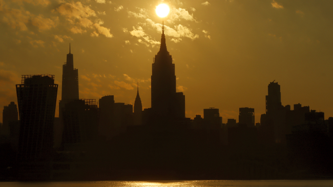 Photo showing the sun rises above the Empire State Building in New York City on August 4, 2022, as seen from Hoboken, New Jersey. 