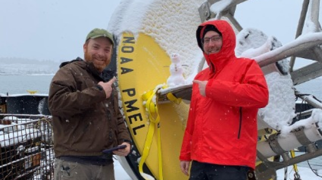 NOAA Pacific Marine Environmental Lab scientists Patrick Berk and Nathan Anderson pose on a research vessel in Alaska.