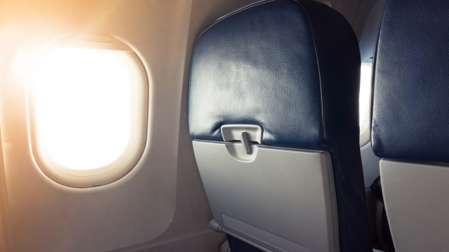Rays of sunshine coming through an airplane window with seatbacks visible. iStock image.