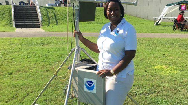 A NOAA employee standing outside with weather monitoring equipment.