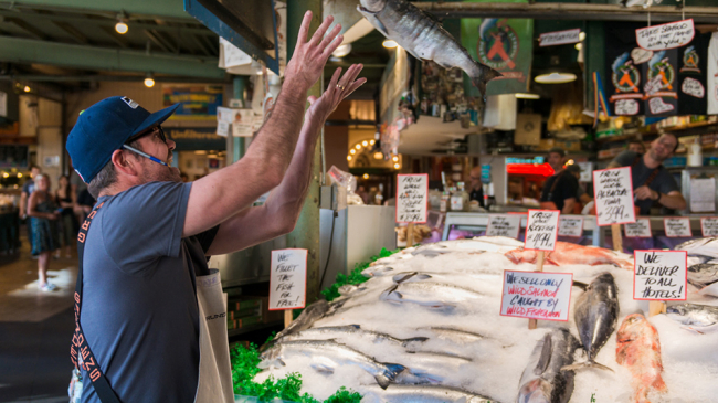 A fish monger catches a fish for tourists at Seattle's Pike Place Market. 