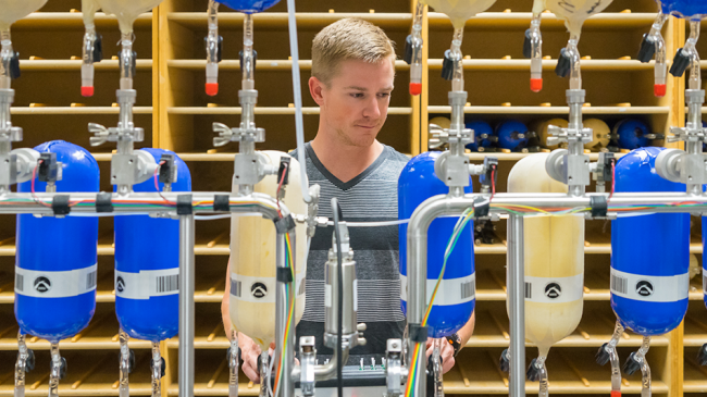 Eric Moglia, of NOAA's Cooperative Institute for Research in Environmental Sciences, pumps air from sampling flasks to test them for leaks before preparing them for shipment to some 80 sites around the world.