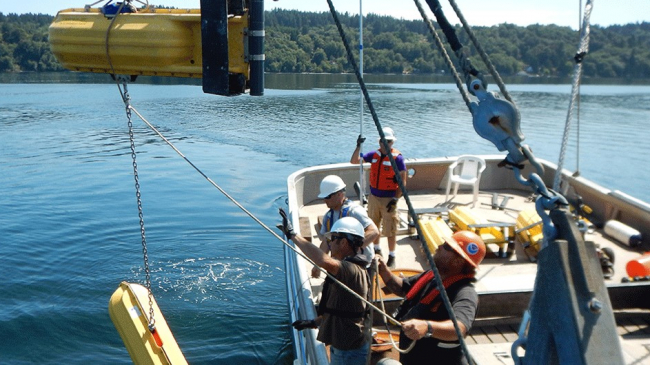A NOAA team deploys a current meter with surface floats to take measurements throughout the water column during surveys of Puget Sound.