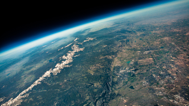 The view from an ozone balloon floating 100,000 feet above the Colorado Front Range. NOAA scientists based in Boulder, Colorado launch weekly balloons from sites all around the globe to monitor stratospheric ozone concentrations. Floating to over twice the altitude of commercial airliners, the curvature of Earth and inky black of space are clearly visible.