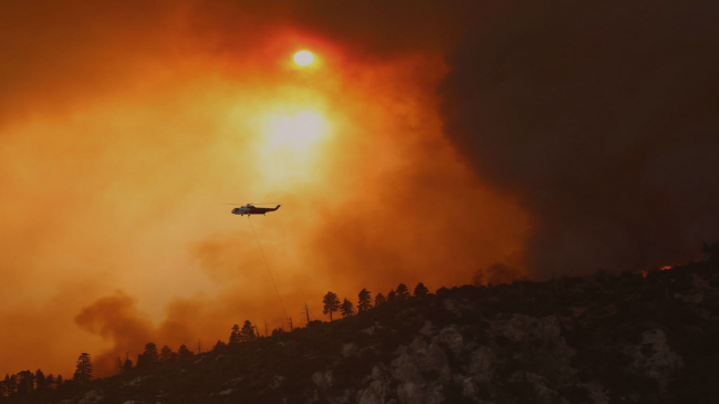 The Bobcat Fire started in and around Angeles National Forest in California on September 6, 2020. As of October 5, the fire has burned through more than 115,000 acres. In this Inciweb photo, a helicopter flies over a portion of the fire to help distinguish it. More information and photos available at Inciweb, www.inciweb.nwcg.gov.