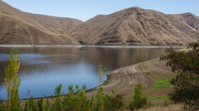A wide view of Idaho's Hells Canyon reservoir in drought, showing a dry shoreline and receding waterline. 2018 photo.
