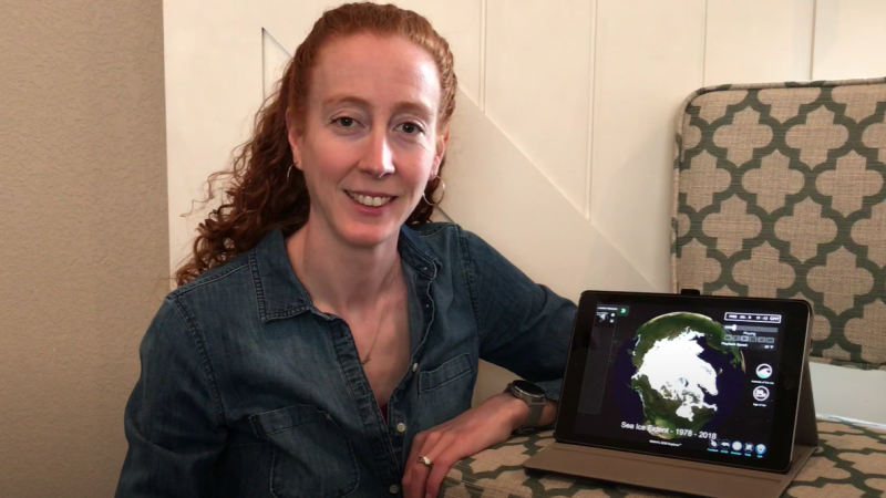Beth poses next to an iPad displaying science on a sphere