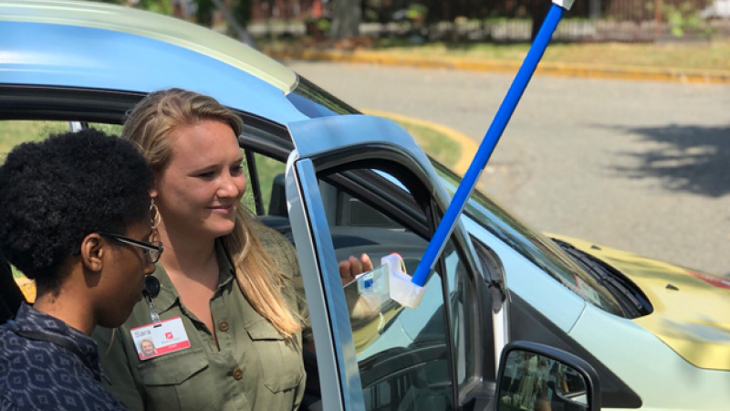 Sara Benson (right) and Roxanne Lee, of the Boston Science Museum, using a CAPA Heat Strategies sensor to investigate extreme heat in Boston, Brookline, and Cambridge, Massachusetts, on July 24, 2019.
Alt text: Two women stand together near a car door as they attach a temperature gauge to the glass window of the car door.