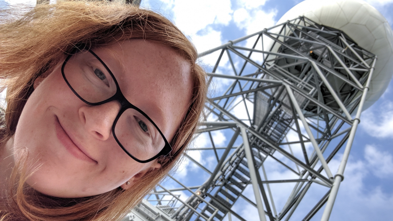 Melissa Piper, a 2018 NOAA Hollings scholar, in front of the Louisville radar (KLVX) in Ft. Knox, Kentucky, on Friday July 12, 2019. Piper conducted her internship at the National Weather Service (NWS) in Louisville, Kentucky, where she analyzed dual-pol digital precipitation rate data for heavy rainfall events in central Kentucky and southern Indiana to determine critical rainfall rates for flash flooding in vulnerable areas.