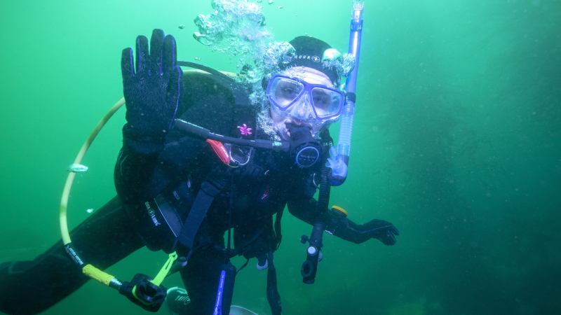 Hannah Brady, a 2018 NOAA Hollings scholar, waves to the camera after having finished taking pre-construction photos of the Monterey Bay Aquarium pipe for her summer internship.