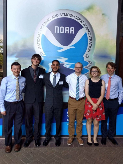 Class of 2019 Hollings scholars gather beside a NOAA logo at NOAA headquarters during the Student Scholarships Orientation Training Program in Silver Spring, Maryland.