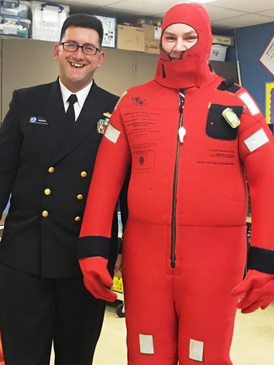 NOAA Corps LT Jonathan Heesch stands with a Seven Seas celebration participant wearing a water survival suit. LT Heesch traveled to the Huntsville event to teach students and parents about ship safety.