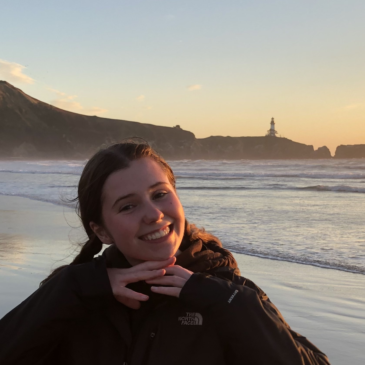 Kaleigh Ballantine smiling in front of the beach at sunset.