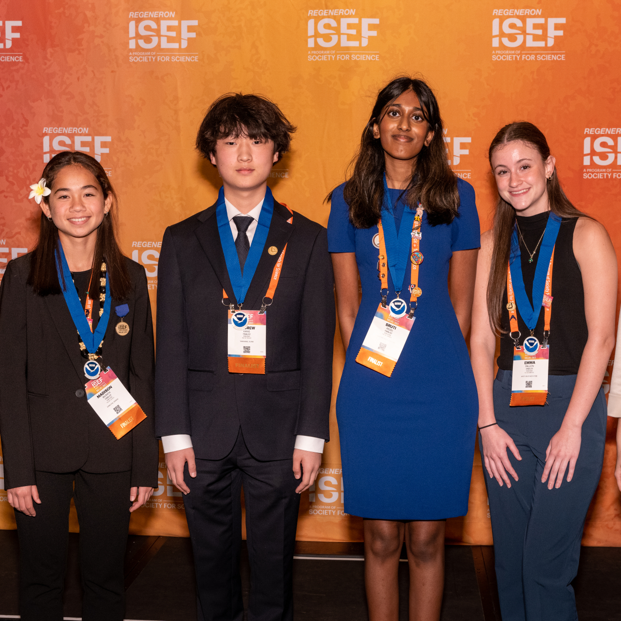 Five smiling high school students wearing blue NOAA award medals standing in front of an orange background. 