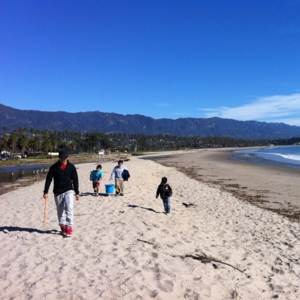  Three students and an adult walking along an empty beach.