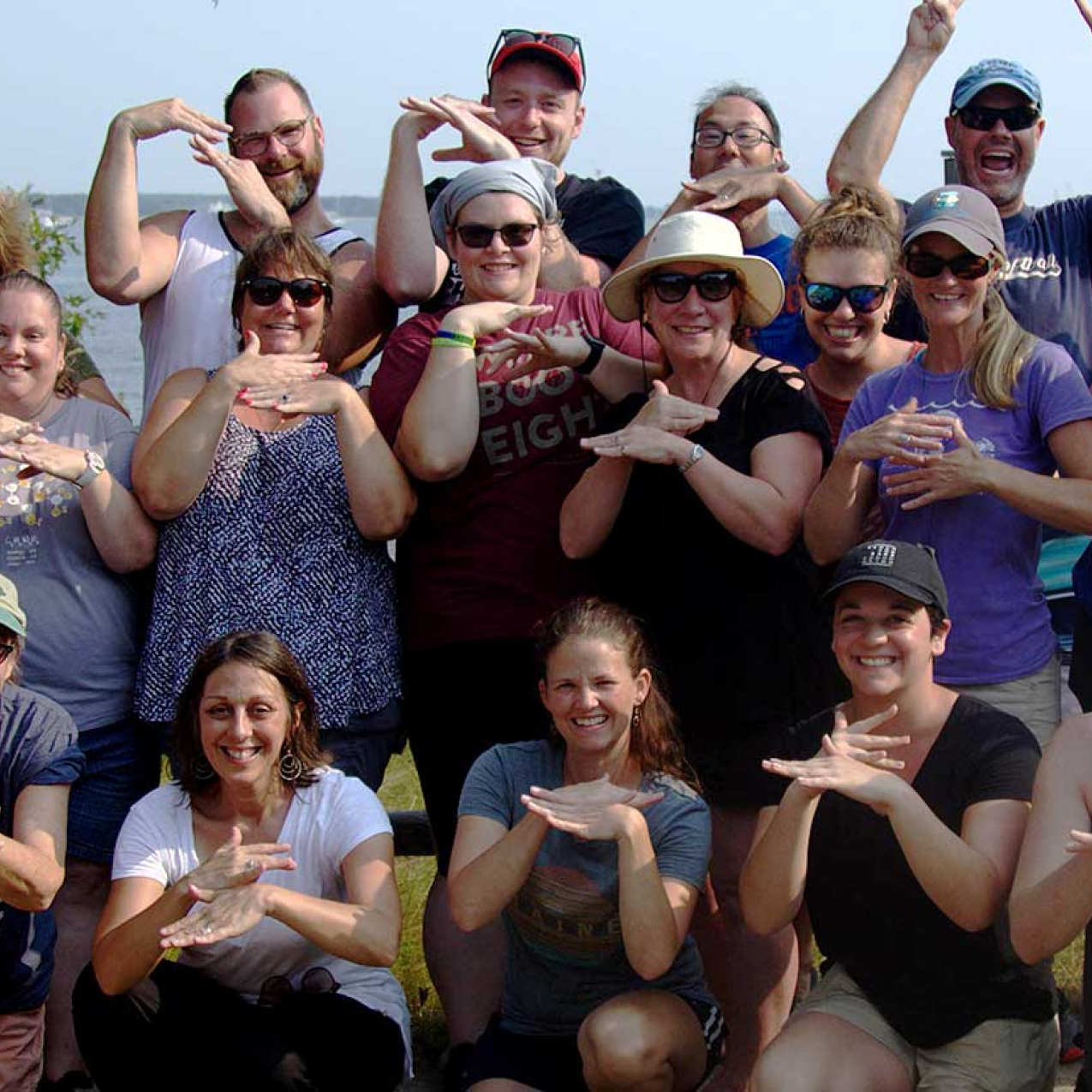 Attendees of a Teachers on the Estuary workshop at Waquoit Bay Reserve demonstrate the new American Sign Language sign for "estuary." The sign represents mixing between the river and the sea.