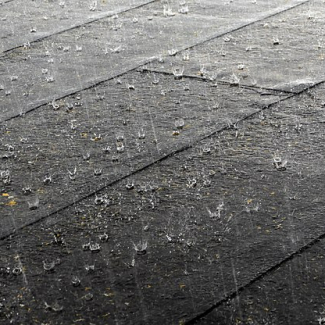 Close up of rain falling on a tiled roof. The rain looks to be falling hard.