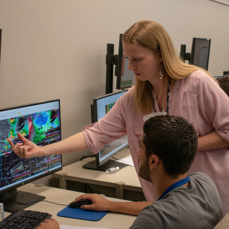 In 2019, University of Oklahoma School of Meteorology Student Ryan Cumming participated in a severe weather simulation used to train all National Weather Service forecasters. He was one of 26 students who took the "Application of Theory to Severe Thunderstorm Forecasting" course. CIMMS Researcher Jill Hardy supports the NWS Warning Decision Training Division training and points out some areas to Cumming that he should focus on. 
